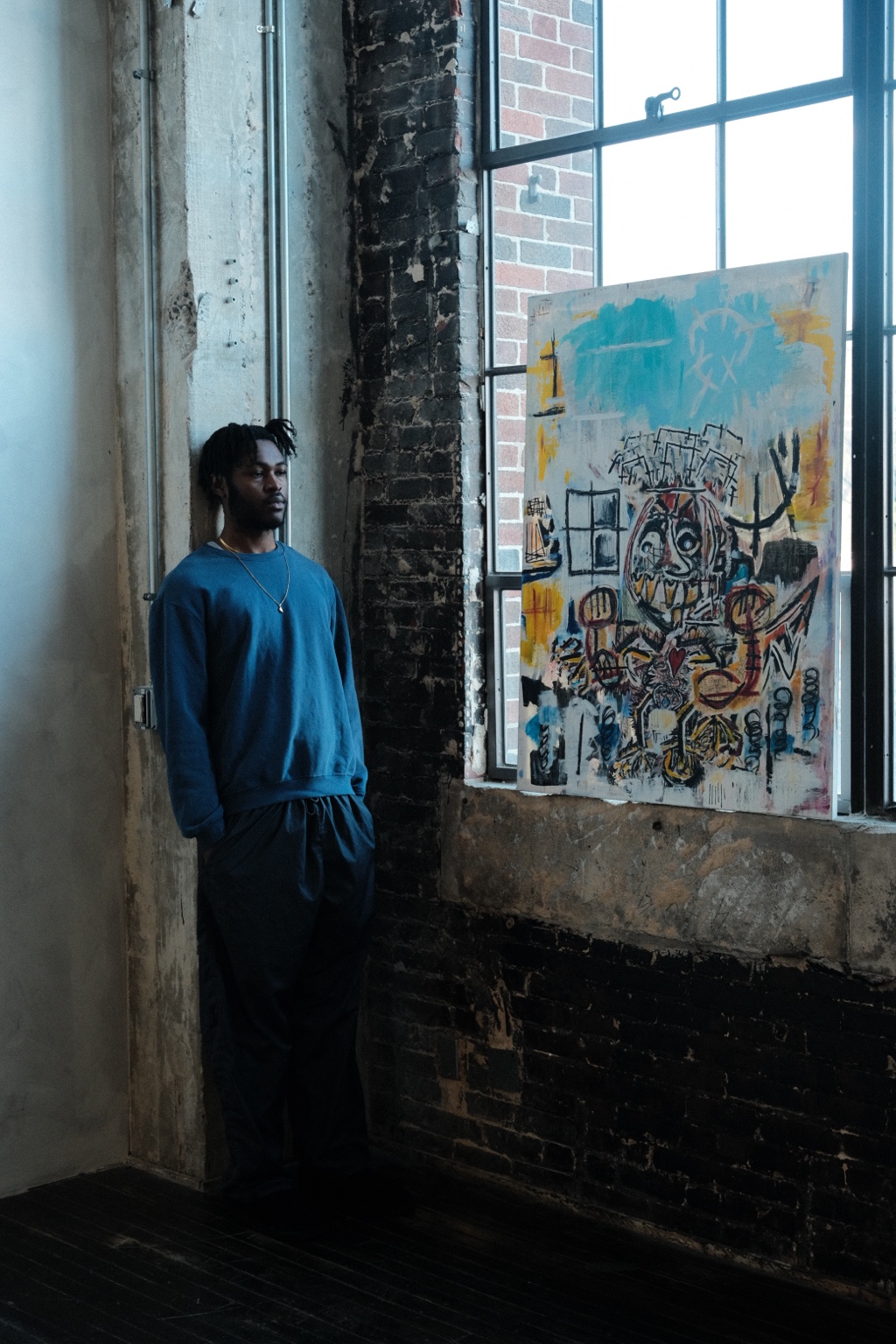 Jon John standing beside one of his paintings